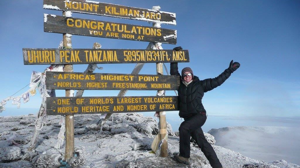 Christine Germain posing with a sign on Mount Kilimanjaro