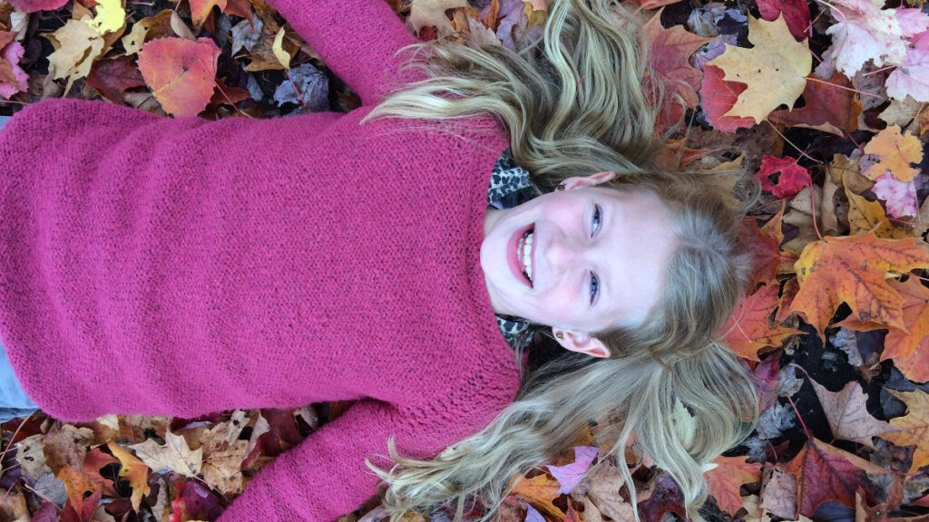 Smiling girl laying on autumn leaves