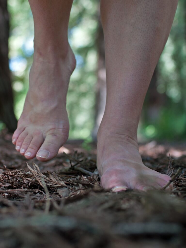 Christine Germain's feet, walking on a mulch pathway in the forest.